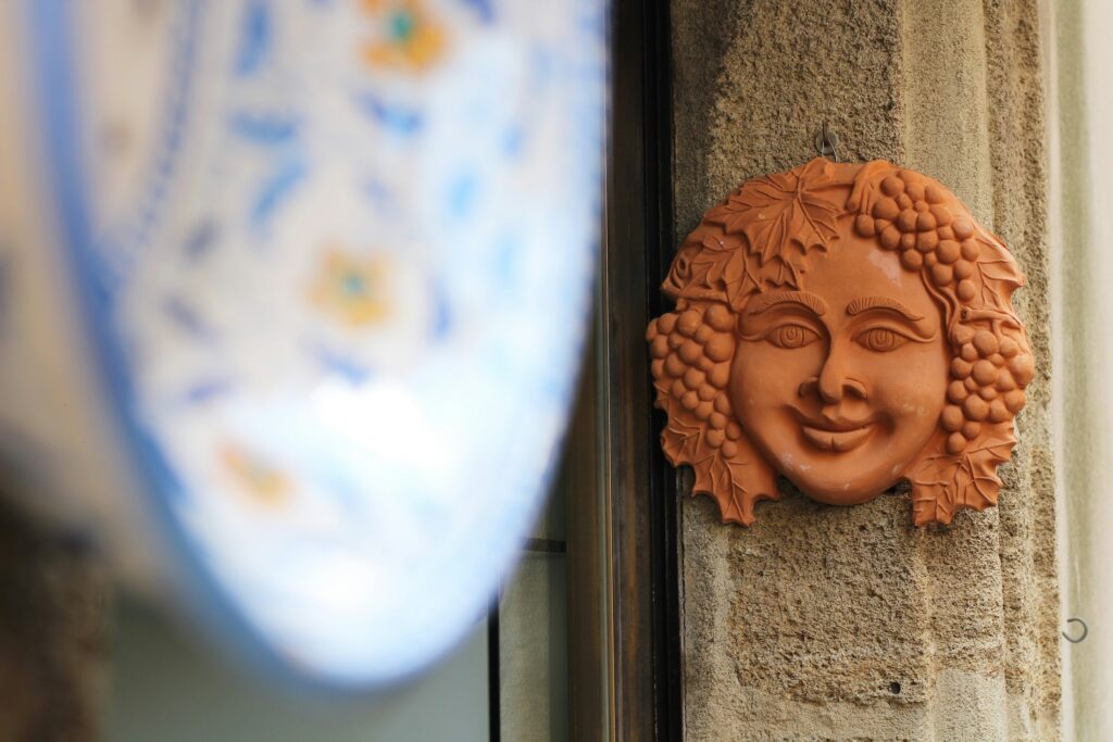 A soft-focus Italian dish in the foreground, with clay mask in background