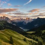 The sun sets across a sweeping mountain valley
