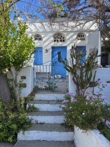Greek home on Tinos with classic blue doors in white structure. Boundless Journeys Greece hiking tour will take you through these very streets.