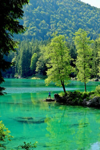 Photo of hiker overlooking turquoise stream on Alpe Adria trail