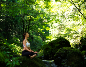 Photo of woman meditating in the woods: example of wellness travel